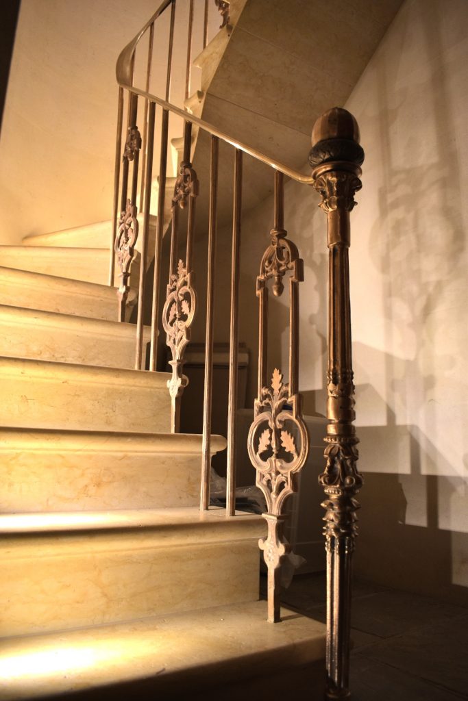 Foot of bespoke spiral staircase with solid bronze handrail.
