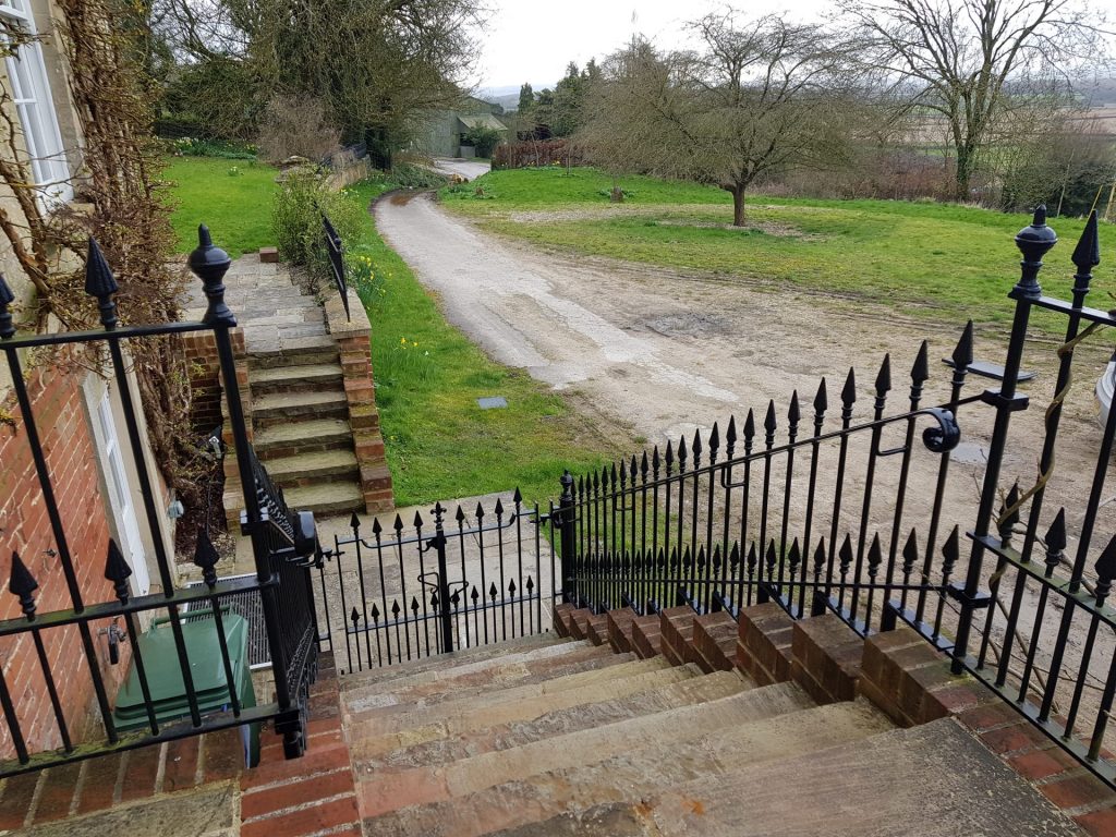 View down exterior staircase of bespoke wrought iron balustrades and gates.
