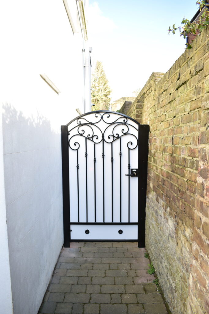 Black wrought iron side gate with white sheeting.